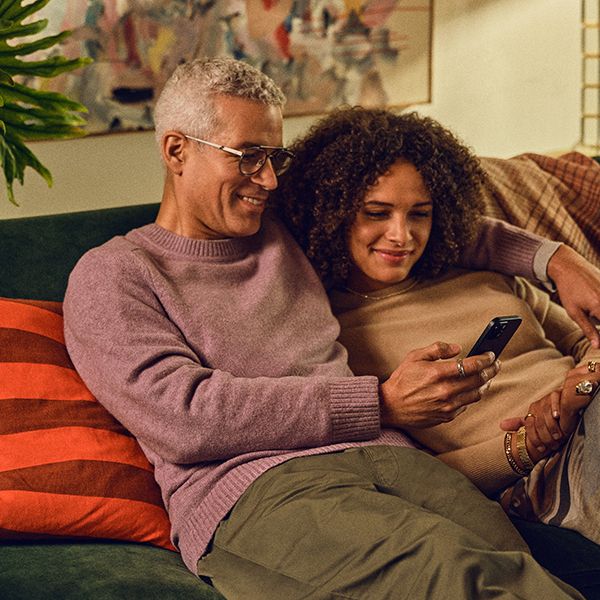 Ein Pärchen auf dem Sofa und beide schauen in ein Handy