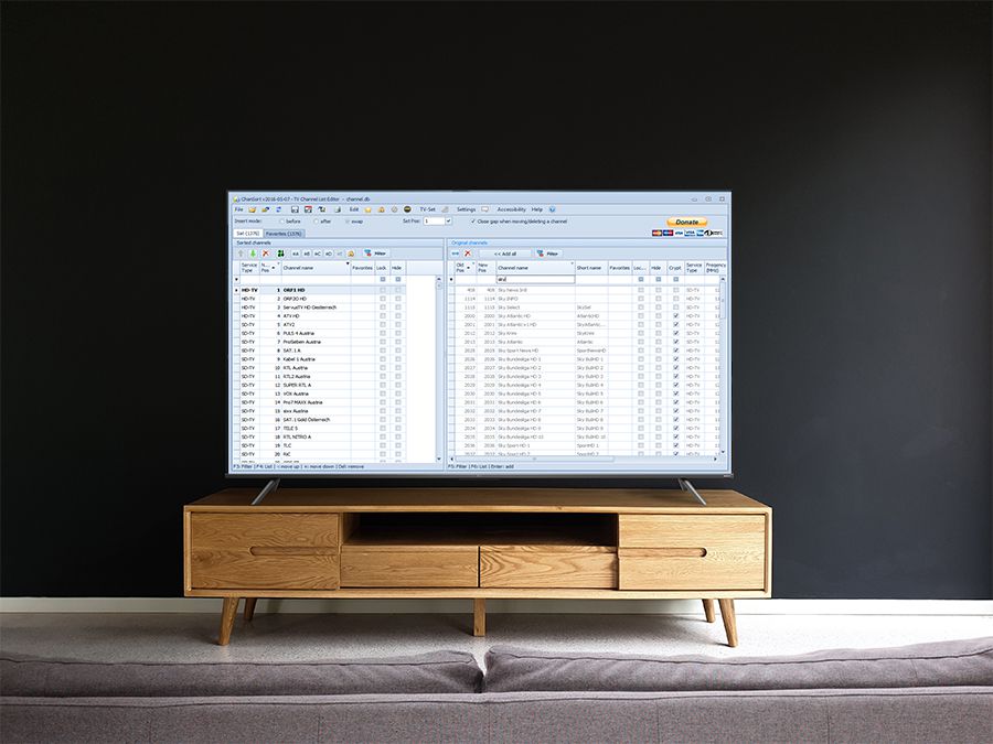 Eine Frontalansicht eines TCL-TVs auf einer Holzkommode vor einer Schwarzen Wand