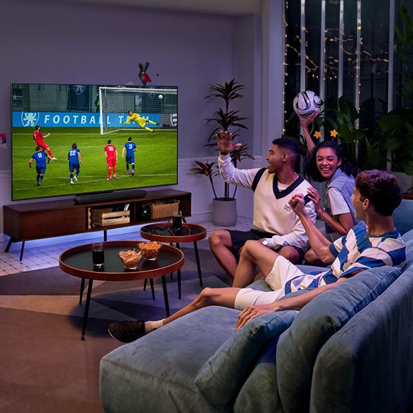 Lifestylebild von einem TCL 98 Zoll Fernseher mit Fussballfans auf der Couch